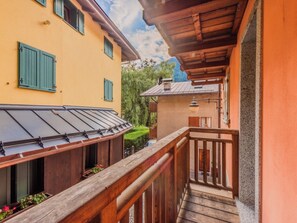 A balcony with a wooden railing overlooking a street with buildings. - Apartment Rugia by Interhome (Pinzolo)