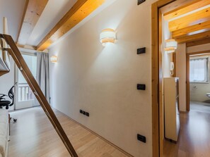 A modern interior with a wooden ceiling, a staircase, and a hallway leading to a bathroom. - Apartment Rugia by Interhome (Pinzolo)