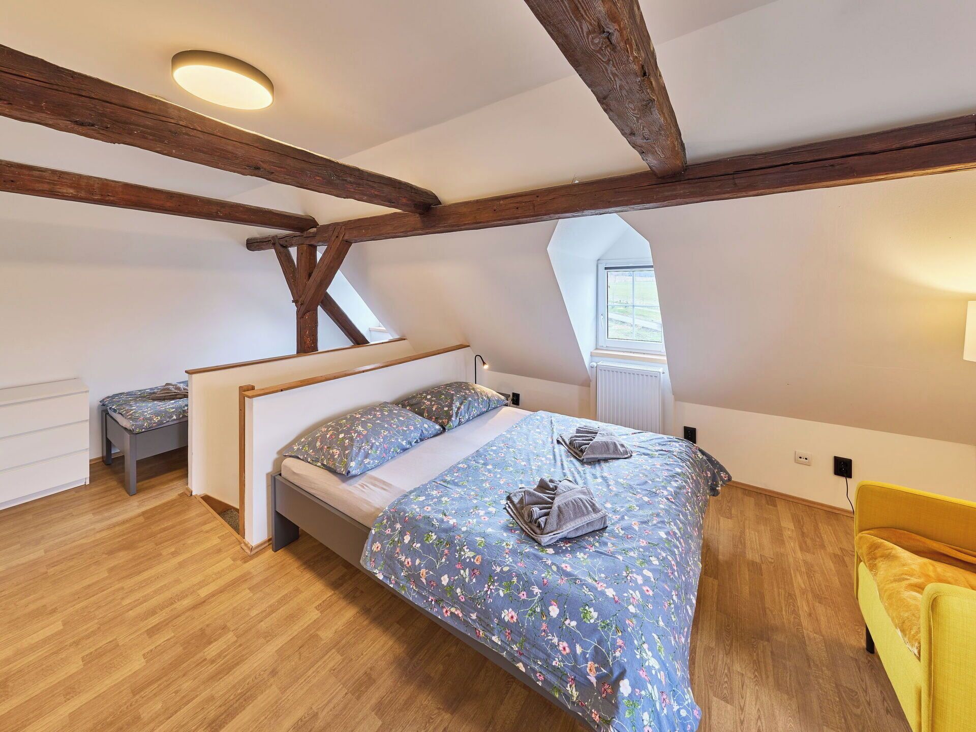 A bedroom with a bed, a bench, and a window.