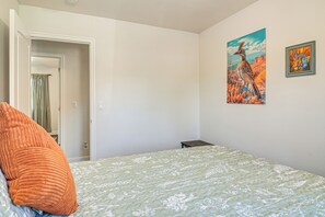 Une chambre à coucher comprenant un lit, un oreiller, une table de chevet et deux œuvres d’art murales.