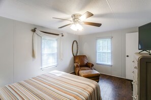 A bedroom with a bed, a chair, a ceiling fan, and two windows with blinds. - Waterfront Nature Escape on Altamaha River (Uvalda)