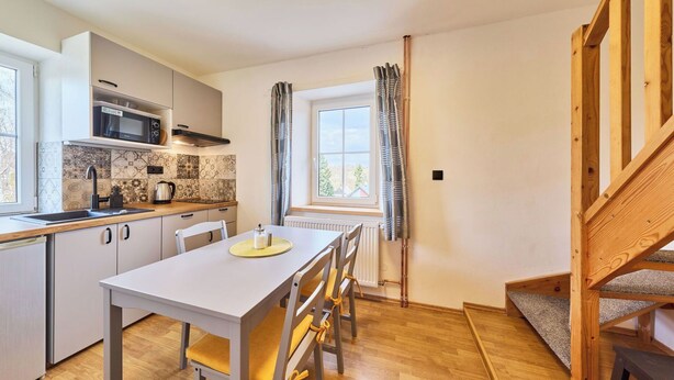 Cozinha moderna com mesa de jantar, cadeiras e vista para o exterior.