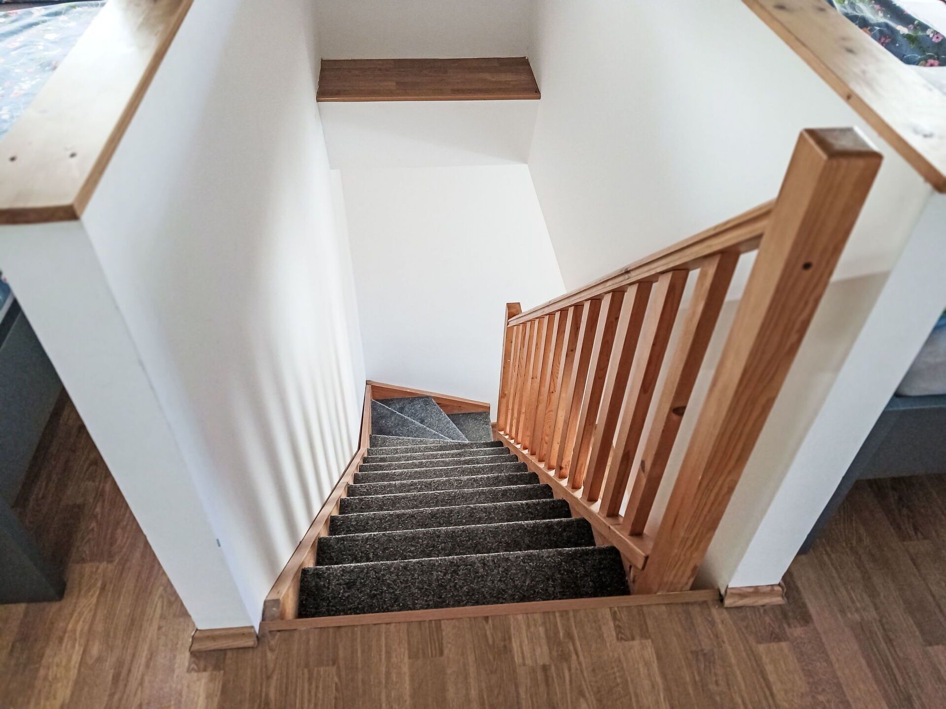 A wooden staircase with a handrail leading to a landing.