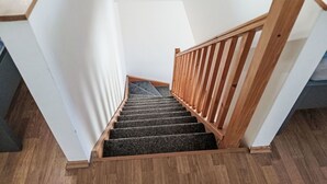 Uma escada de madeira com corrimão que leva a um patamar.