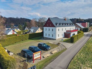 Ein Wohngebäude mit Parkplatz und drei geparkten Autos davor.