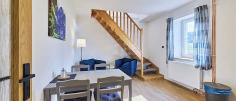 A modern living space with a dining area, a staircase, and a view of the outdoors.