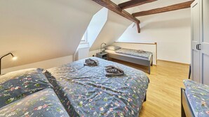 Een slaapkamer met twee bedden, een houten plafond en een dakraam.