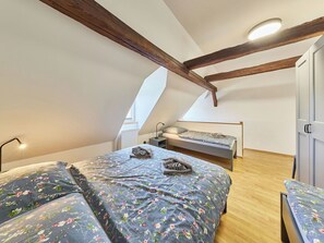 Ein Schlafzimmer mit zwei Betten, einer Holzbalkendecke und einem Oberlicht.