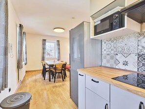 Cocina compacta con refrigerador, microondas y comedor con mesa y sillas.