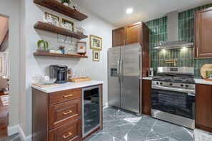A kitchen with a refrigerator, stove, and oven. There are wooden cabinets and a countertop with various items.