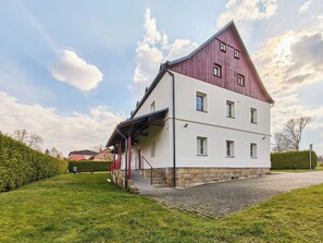 Ein zweistöckiges Gebäude mit einem geneigten Dach, einer überdachten Veranda und einem gepflasterten Auffahrt.