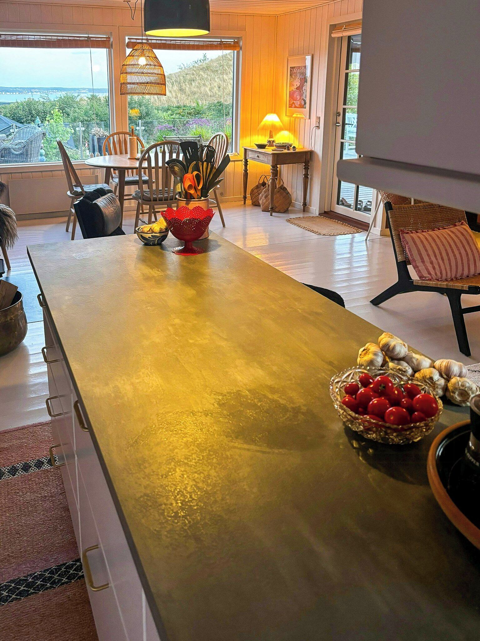 A kitchen with a long island, a dining area with chairs, and a view of the outdoors.