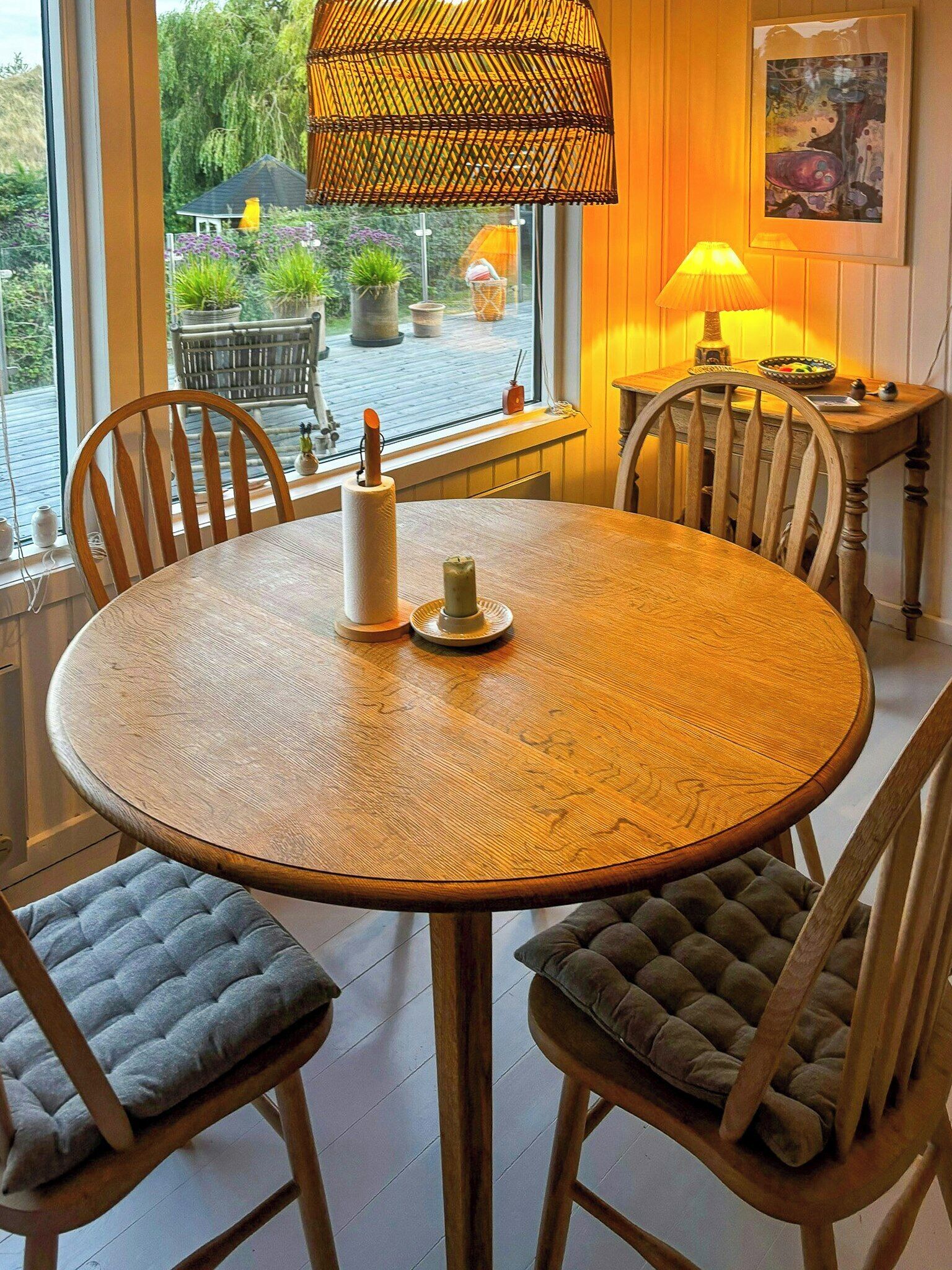 A round wooden dining table with two chairs, a candle, and a paper towel holder.