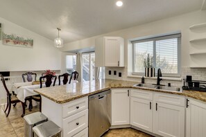 A modern kitchen with white cabinetry, a granite countertop, and a dishwasher. - Gateway to Mountain Fun! 5BR Utah Home (Lehi)
