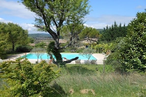 Ein Schwimmbad, umgeben von Bäumen, mit einem Haus im Hintergrund.