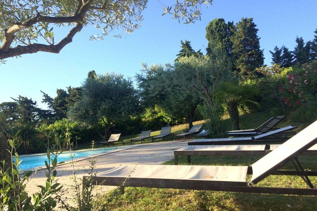 A poolside area with lounge chairs and a swimming pool surrounded by trees.