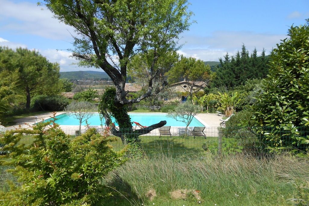 A swimming pool surrounded by trees and a house in the background.