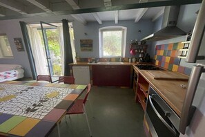 Eine kleine Küche mit Esstisch, Stühlen, Kühlschrank und Herd.