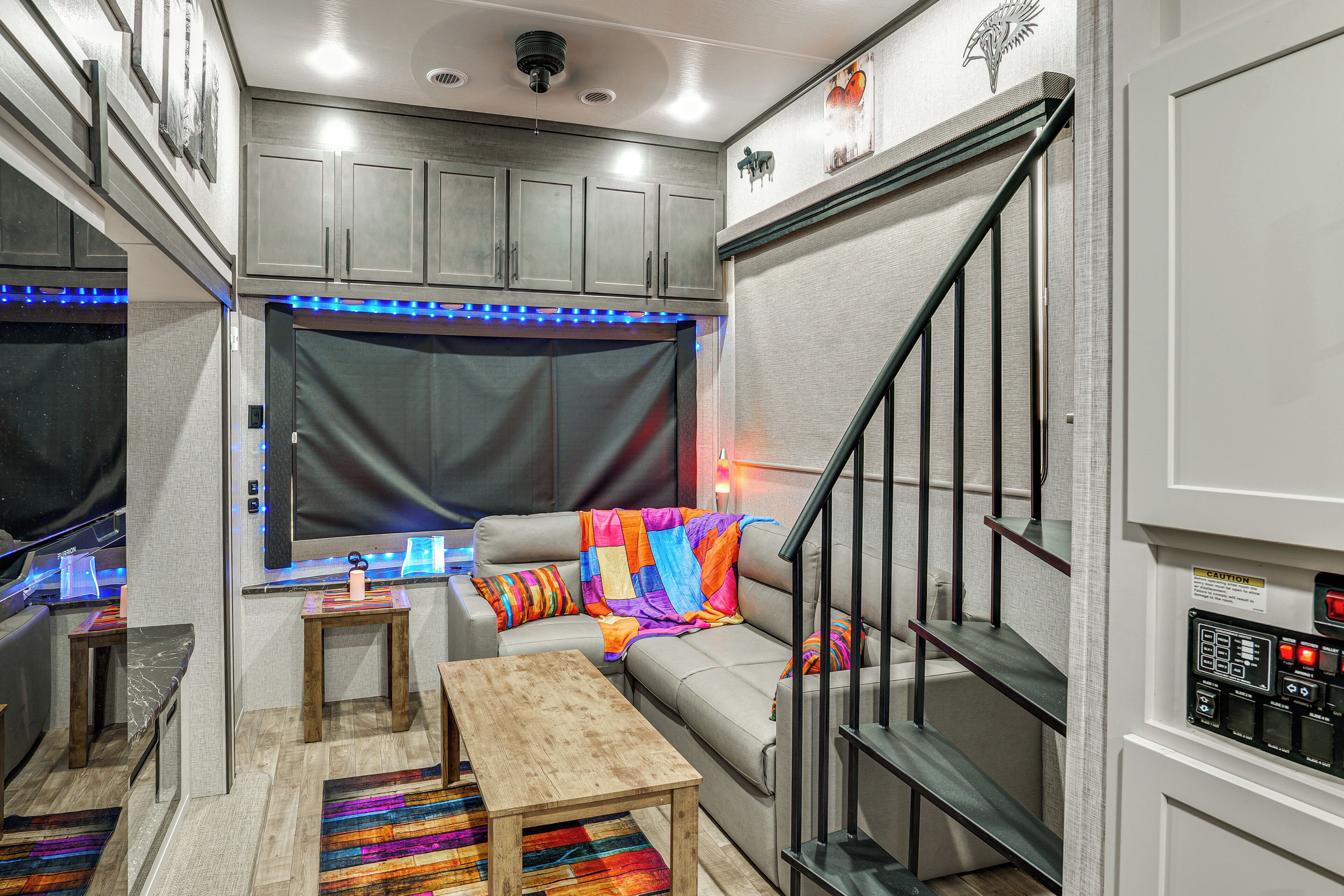 Un espacio habitable compacto con sofá, una mesita, una escalera y una zona de cocina con armarios.