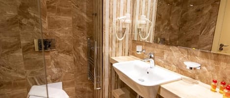 A modern bathroom with a glass-enclosed shower, a white sink with a mirror, and a toilet.