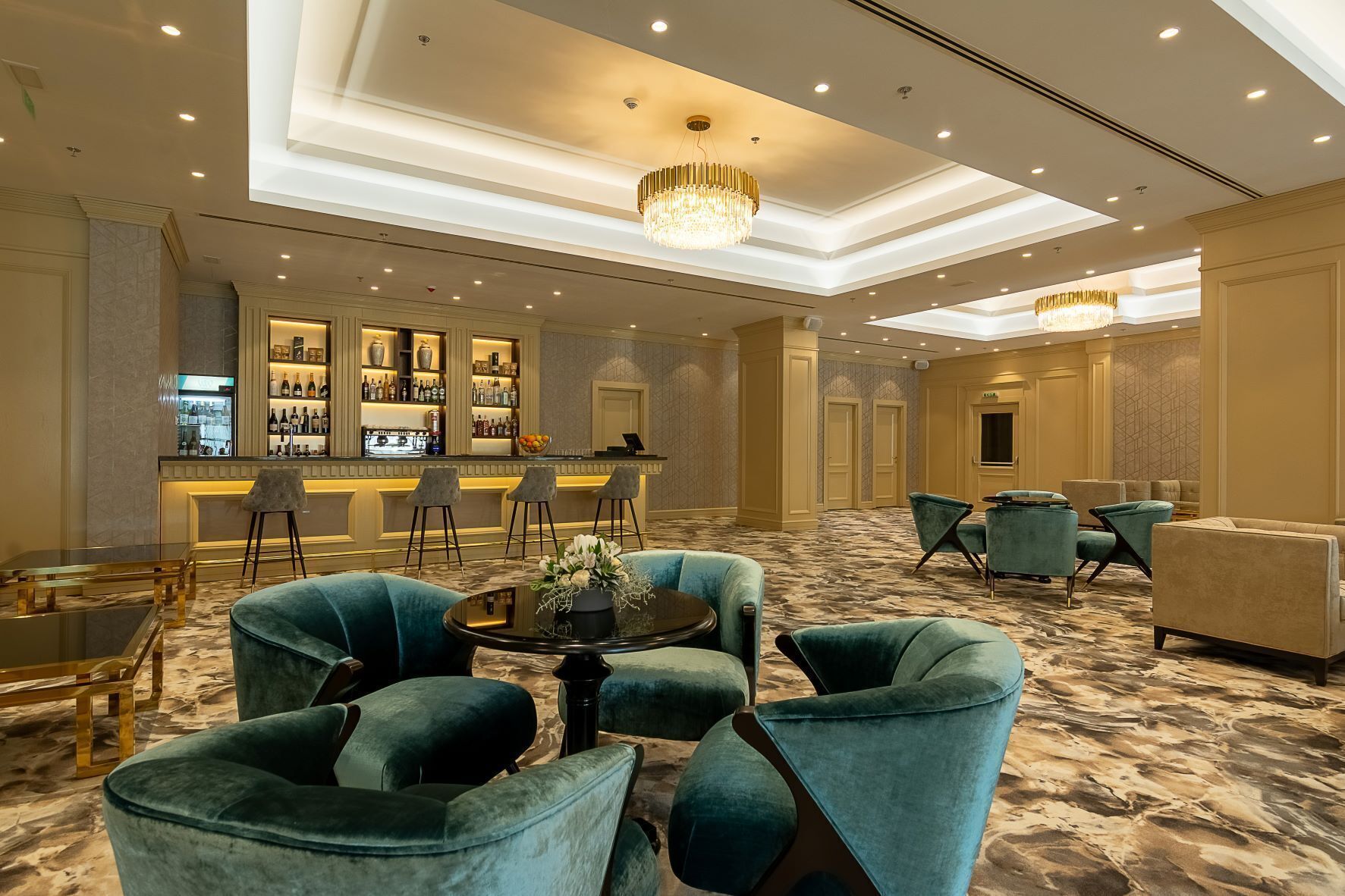 A hotel lobby with a bar area, seating, and a chandelier.