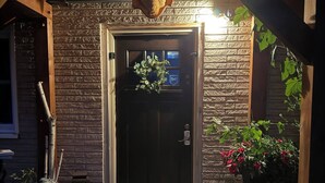 A wooden door with a bell, a mailbox, and a small step leading to the entrance.