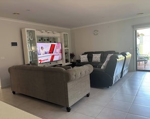 Una sala de estar con una televisión de pantalla plana, un sofá y un sofá de cuero negro.