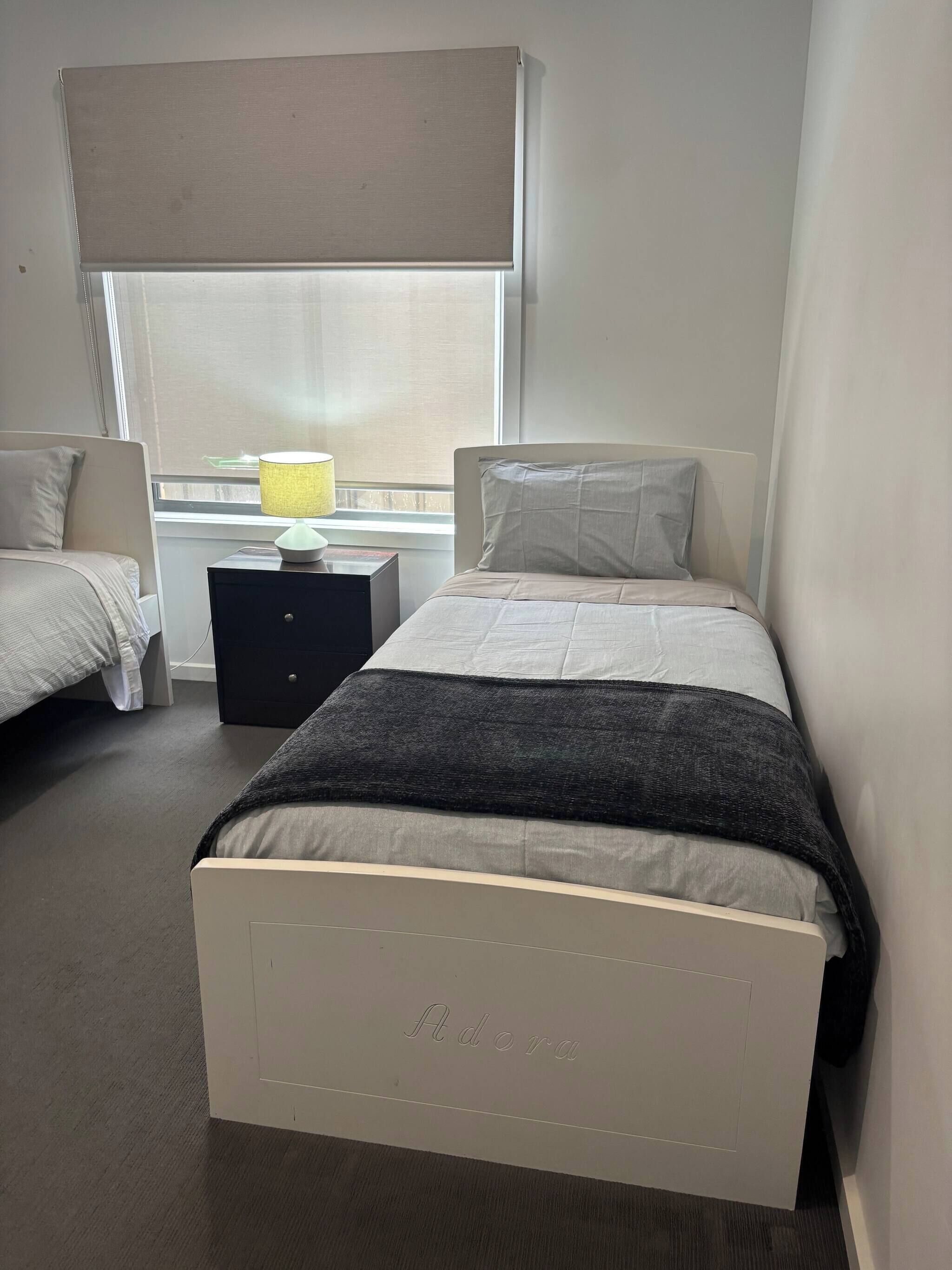 A bedroom with a bed, bedside tables, a lamp, and a window with a blind.