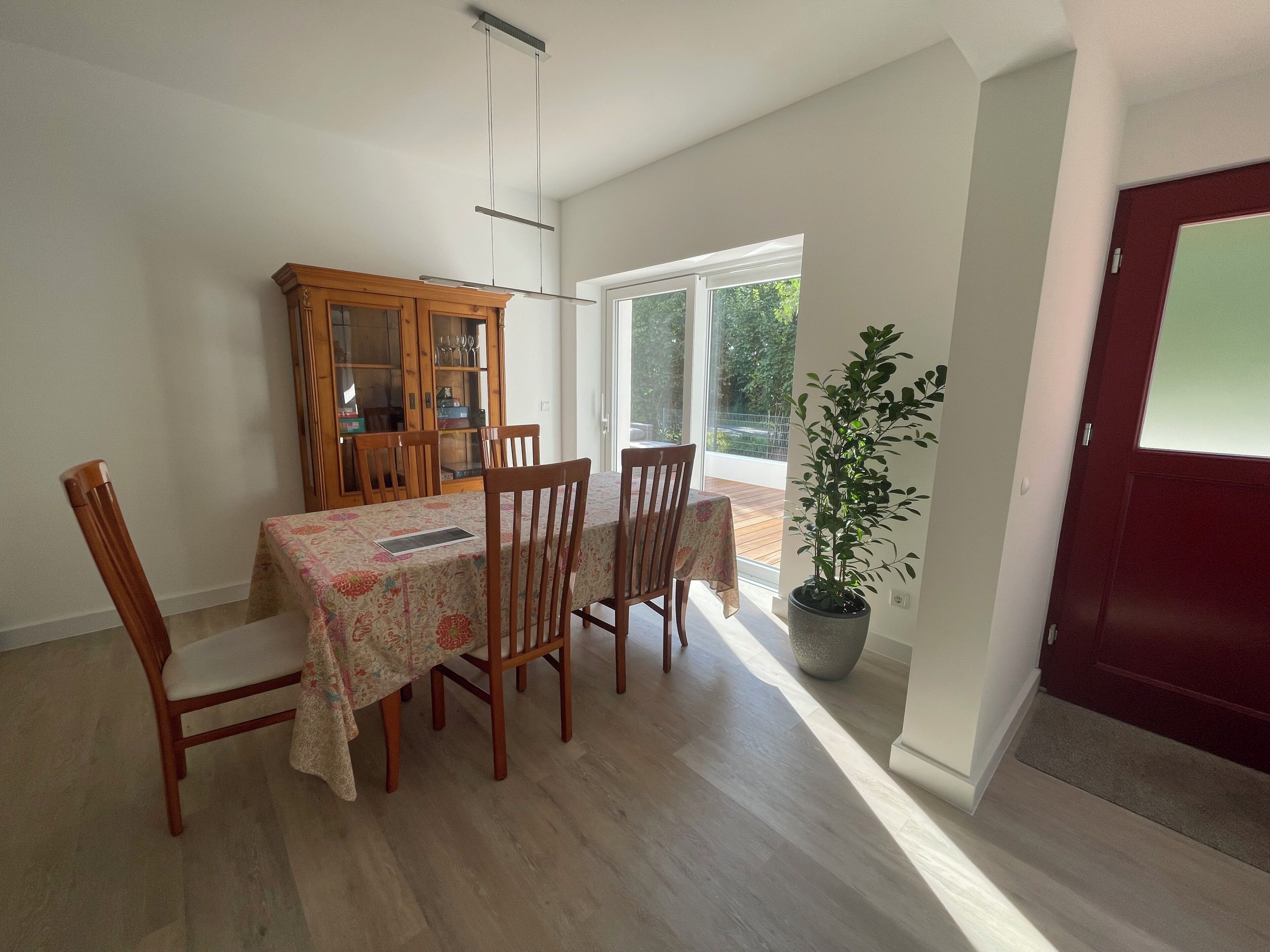 Un coin repas comprenant une table, des chaises, un meuble et une plante en pot.
