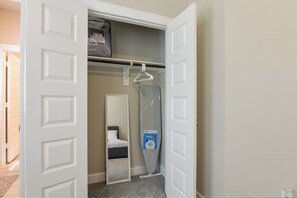 A hotel room with a closet, a hanging garment, a mattress, and a mirror. - Modern Efficiency Studio Near NRG & Medical Center (Houston)