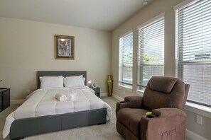 A bedroom with a bed, a chair, a nightstand, a vase, and a picture on the wall. - Modern Efficiency Studio Near NRG & Medical Center (Houston)