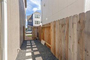 A narrow pathway with a wooden fence on one side and a building on the other. - Modern Efficiency Studio Near NRG & Medical Center (Houston)