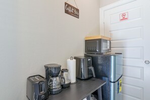 A kitchenette with a coffee maker, toaster, microwave, and refrigerator. - Modern Efficiency Studio Near NRG & Medical Center (Houston)