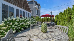 A patio with a round wooden table and chairs, surrounded by white hydrangea bushes. - Normandy Beach! Phenomenal Ocean Block Location (Lavallette)
