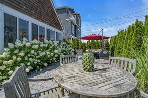 A patio with a round wooden table and chairs, surrounded by white hydrangea bushes. - Normandy Beach! Phenomenal Ocean Block Location (Lavallette)