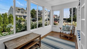 A sunlit room with large windows, a wooden bench, a striped rug, and a chair with a cushion. - Normandy Beach! Phenomenal Ocean Block Location (Lavallette)