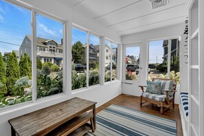 A sunlit room with large windows, a wooden bench, a striped rug, and a chair with a cushion. - Normandy Beach! Phenomenal Ocean Block Location (Lavallette)