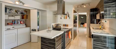 A modern kitchen with a central island, built-in appliances, and a view into the dining area.
