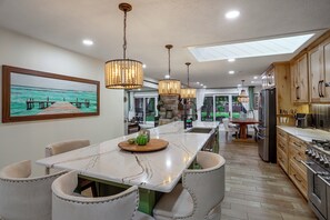 Una cucina moderna con isola centrale, illuminazione a sospensione e vista sull'esterno.