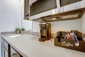Eine moderne Küche mit Edelstahlgeräten, einer Kaffeestation und einem Spülbecken.