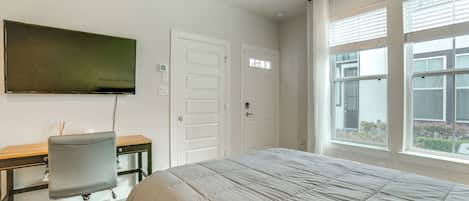 A bedroom with a bed, a desk, a chair, and a television.