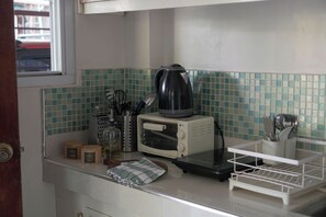 A kitchen with a microwave, kettle, and various utensils.