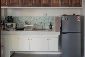 A kitchen with wooden cabinets, a stainless steel refrigerator, a toaster, and a sink.