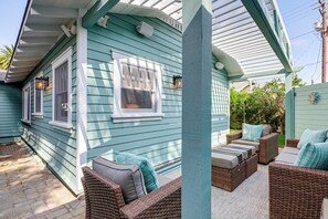 A covered porch with wicker furniture and a window overlooking a garden. - Stroll to Redondo Beach: Modern, Coastal Gem (Redondo Beach)