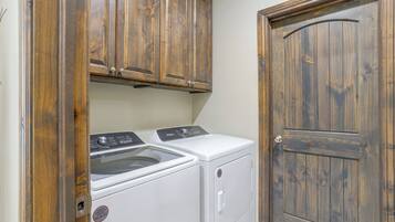 Une buanderie équipée d’un lave-linge et d’un sèche-linge, de placards en bois et d’une porte.