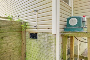 A wooden fence with a small window and a green outdoor unit attached to a house. - 3 Mi to Assateague Beach! Home w/ Furnished Deck (Chincoteague)