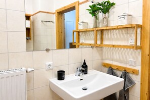 A bathroom with a white sink, a mirror, a towel rack, and a shelf with toiletries. - Apartment on the ski slope (Bad Kleinkirchheim)