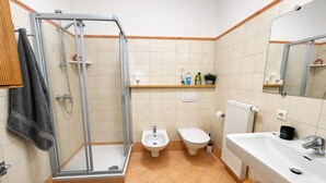 Ein Badezimmer mit Dusche, Bidet, Toilette, Waschbecken und Spiegel.