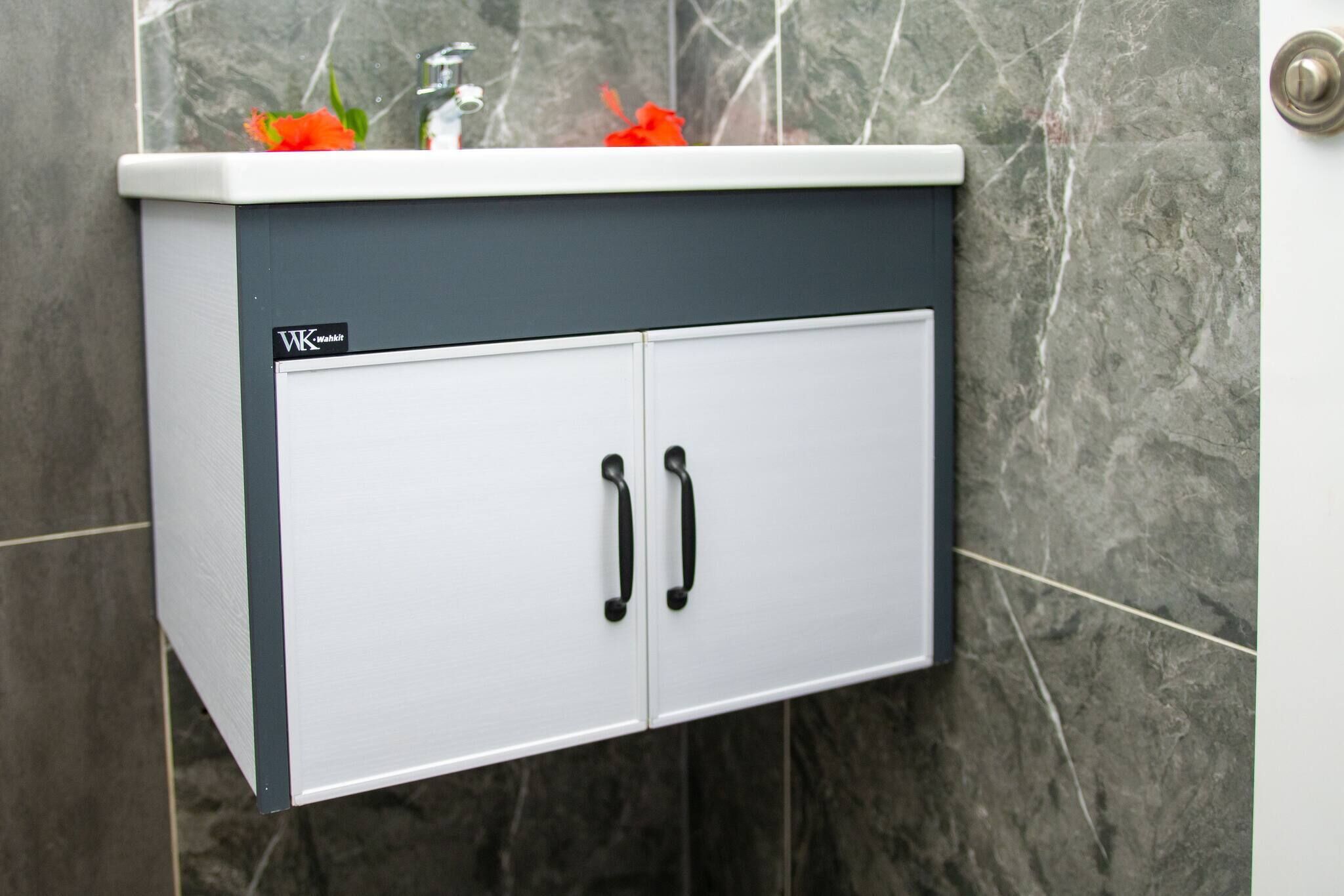 A bathroom cabinet with two doors and a countertop, mounted on a wall with a marble finish.