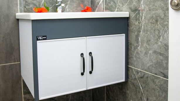A bathroom cabinet with two doors and a countertop, mounted on a wall with a marble finish.